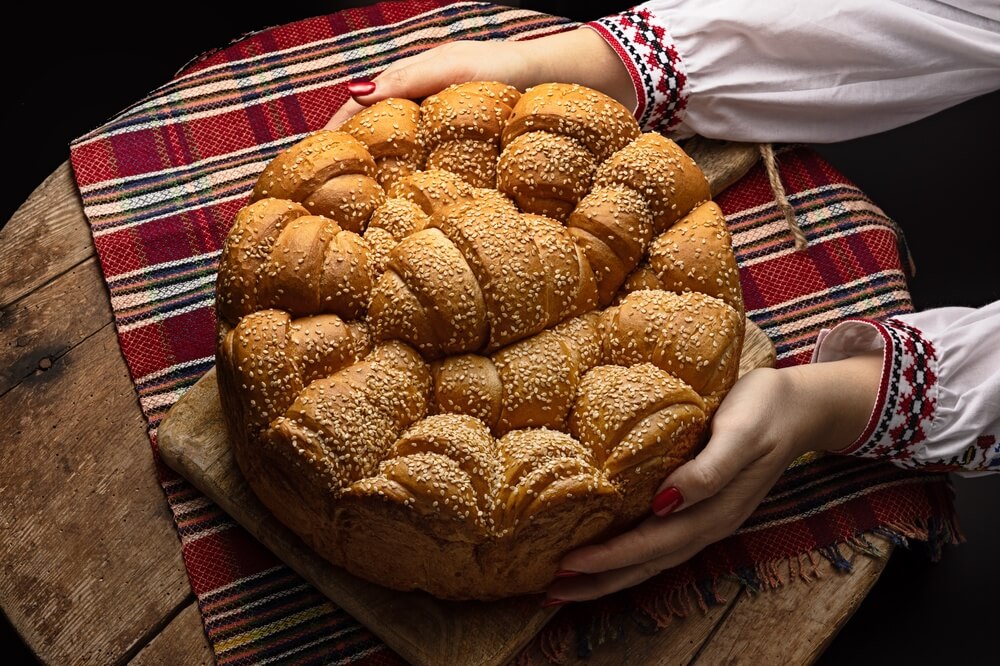 Slávnostný remeselnícky domáci okrúhly chlieb a ruky bulharskej ženy